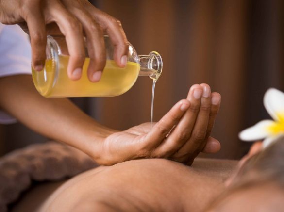 therapist-pouring-massage-oil-at-spa-GWM6LQV-min